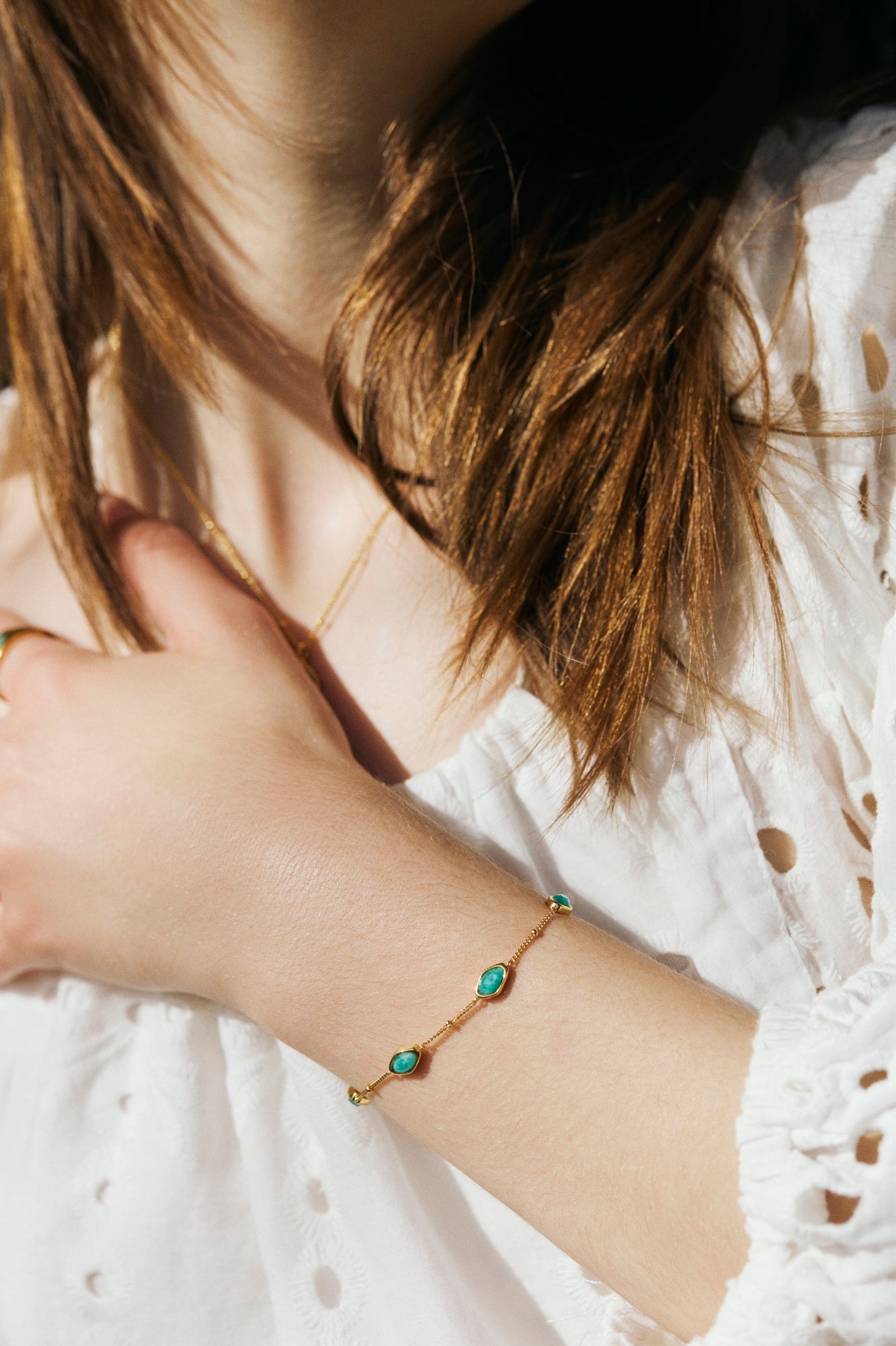 Close-up of a person wearing a gold bracelet with amazonite stones.