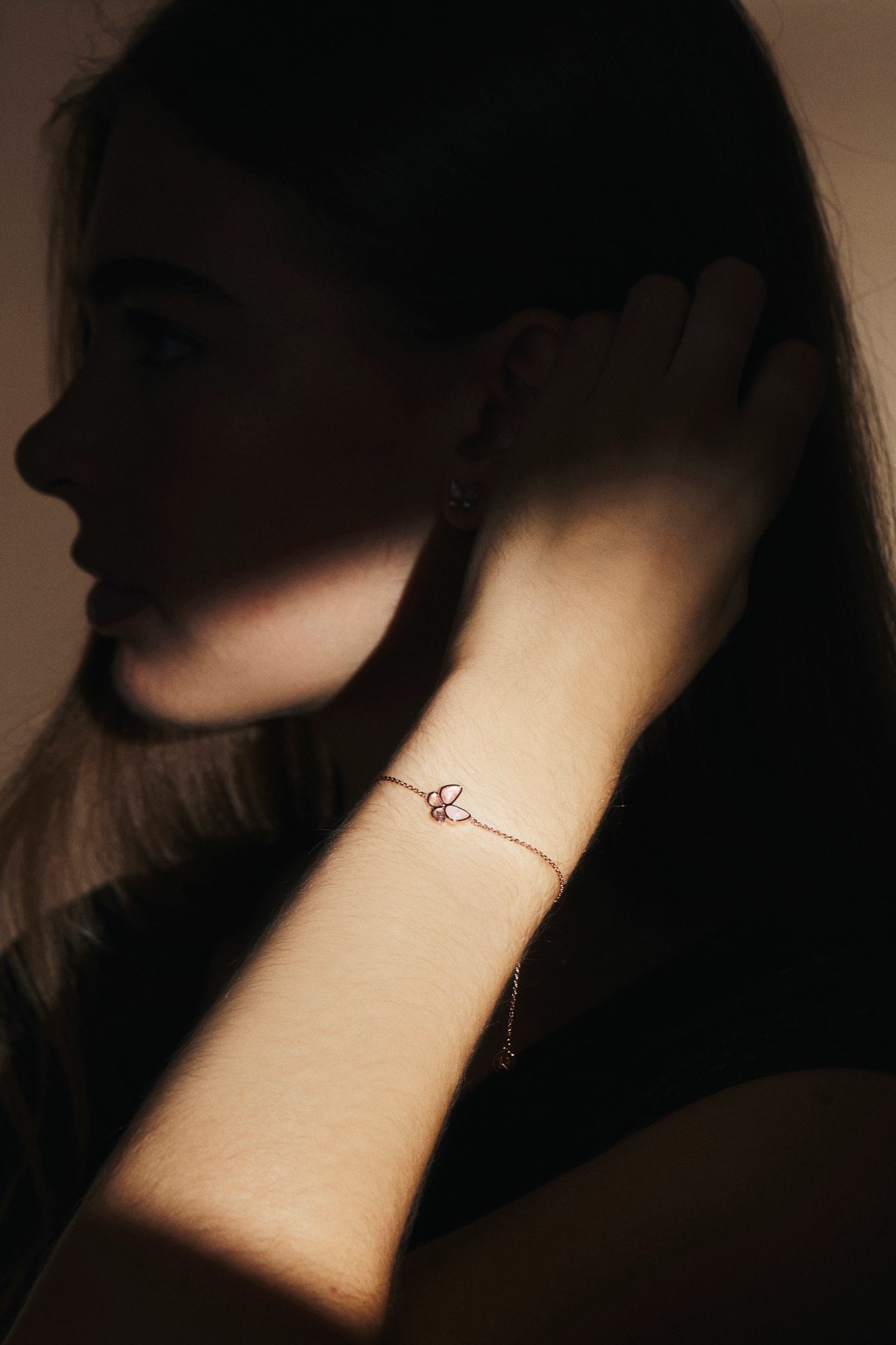 Silhouette of a person wearing a delicate bracelet with a butterfly charm.
